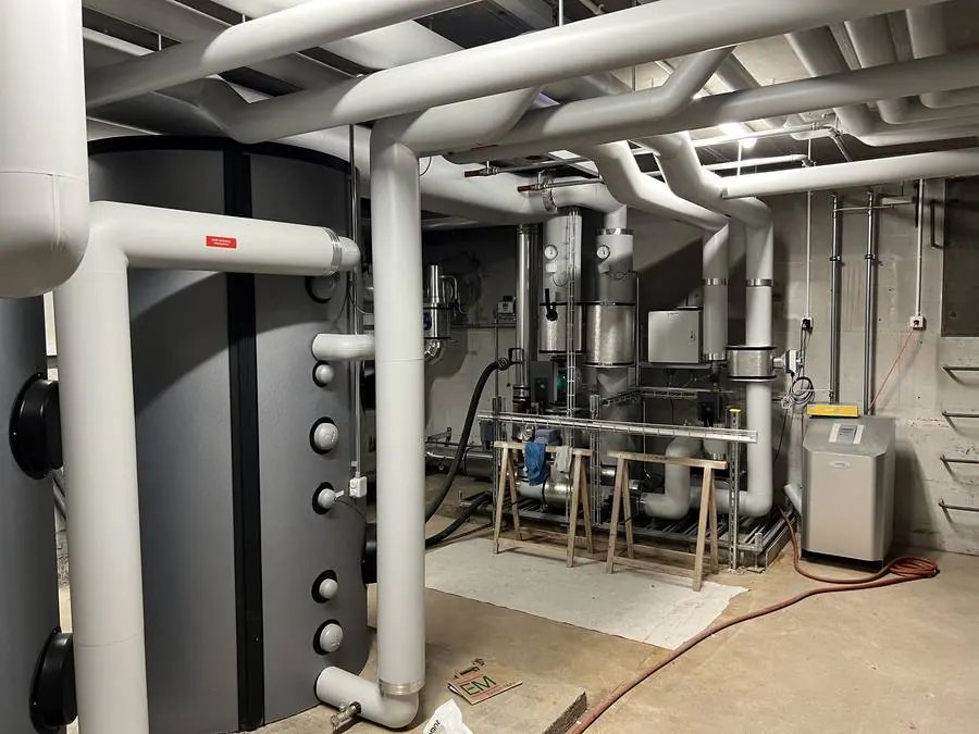 Technikraum in Horgen mit Fernwärme-Anschluss, grossem Speicher und weiss isolierten Leitungen