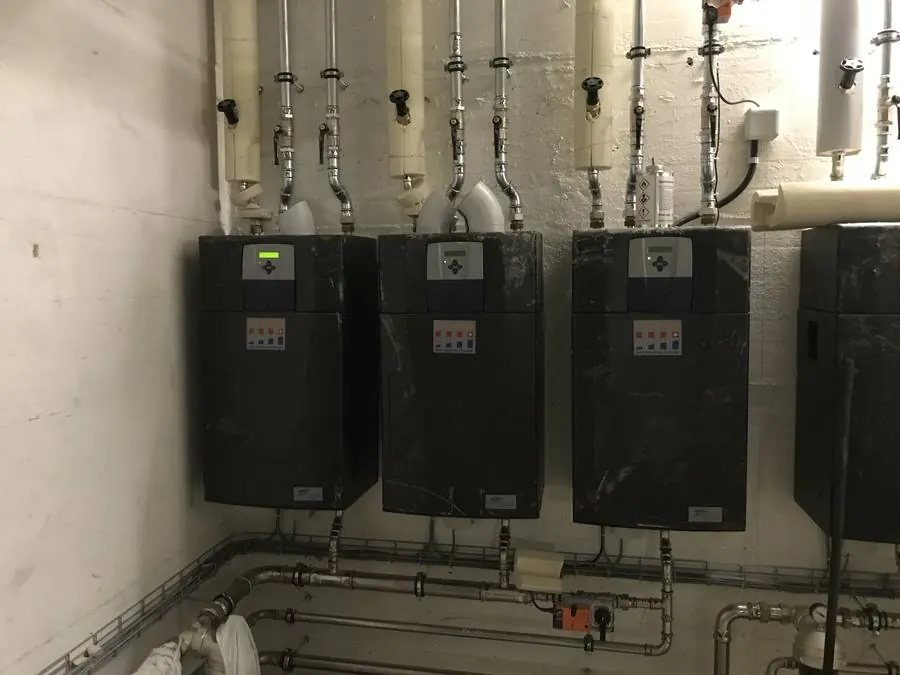 Drei schwarze Frischwasserstationen an der Wand eines Technikraums in Zürich-Altstetten
